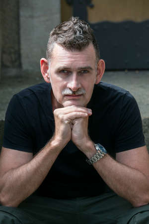 portrait of a handsome man in his 50s wearing a black t-shirt