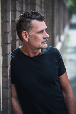 portrait of a handsome man in his 50s wearing a black t-shirt