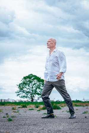 handsome man in white shirt standing outdoors on windy dayの写真素材