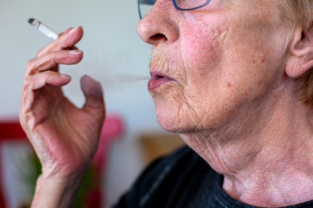 close-up of a wrinkled old woman smoking a cigaretteの写真素材