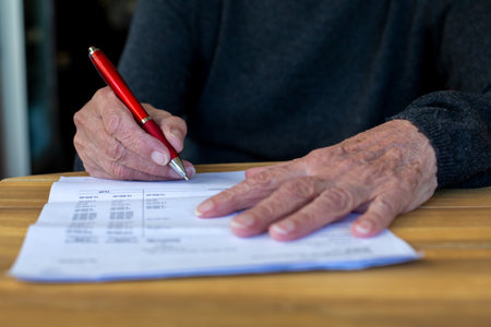 close-up of an older woman's hand signing a paperの写真素材