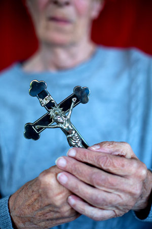 close-up of an older woman holding a cross in her handsの写真素材