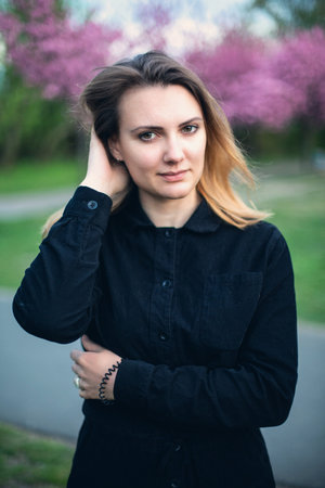 portrait of young brunette woman in park with cherry blossomsの写真素材