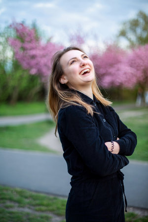 portrait of young brunette woman in park with cherry blossomsの写真素材