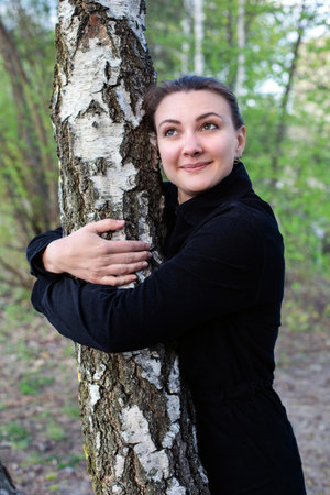 young brunette woman hugging a treeの写真素材