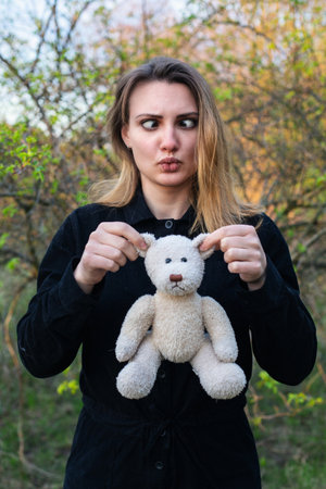 young woman holding a teddy bear and making funny faceの写真素材