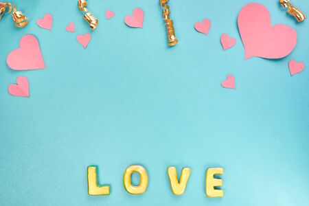 Valentines day concept. Pink paper hearts, confetti and word love on a blue background. Sweet holiday background. Top view, flat lay.の写真素材