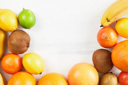 Assortment of tropical fruits orange, tangerine, banana, grapefruit, lemon, lime, kiwi on white background. Fresh fruit set. Copy space.の写真素材