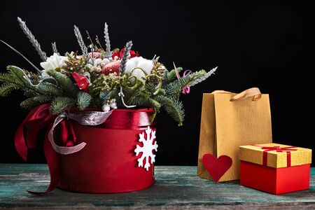 flowers in a paper box with red paper heart and golden paper bag on dark background. Winter bouquet...
