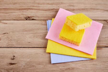 yellow sponge on wooden table with color cloths, top view, close upの写真素材