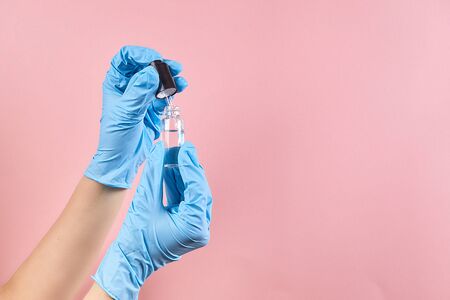 Woman in blue medical gloves holding glass bottle of beauty serum. Beauty product for a skincare...
