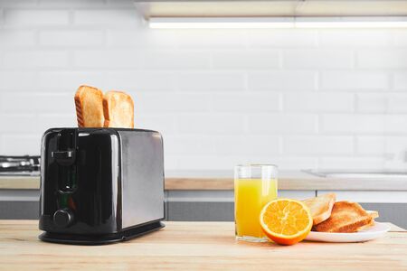 Toaster with dishes and toast with fresh juice on a kitchen table