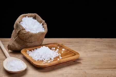 salt in bag and spoon closeup on oak wooden background