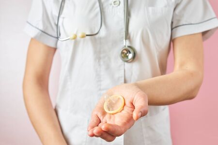 Female doctor holding condom for aids prevention and birth control. Contraceptives in a hands for safe sexの写真素材