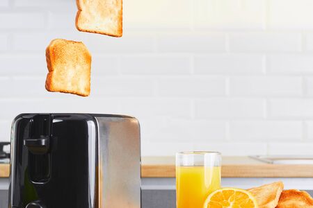 Toaster with dishes and toast with fresh juice on a kitchen table