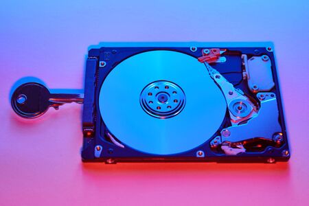 Data security concept. Key on spindle of hard disk drive. Opened Hard disk.