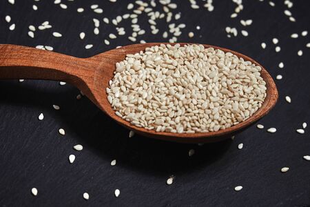 Sesame seeds and a wooden spoon on a dark table. Healthy food and drink concept. Top View. Close upの写真素材