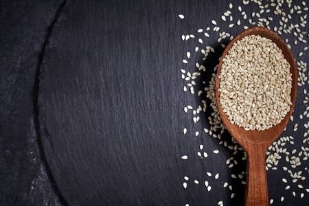 Sesame seeds and a wooden spoon with black slateboard on a dark table. Healthy food and drink concept. Top View. Close upの写真素材