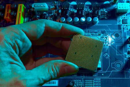 Engineer repairman holding chip CPU to insert into the socket of the computer motherboard. Concept...