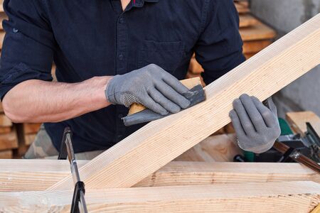 Male carpenter hands using sandpaper on a plank of wood for handmade furniture. Close up. Wooden table.の写真素材