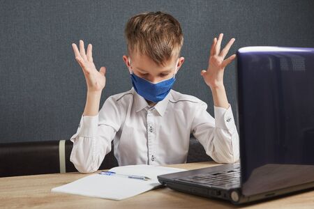 Social distance, self-isolation, online education concept. Boy in mask studying homework math during...