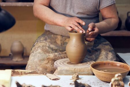 Potter at work. Workshop place. The hands of a potter creating jar on the circle. Close up.の写真素材