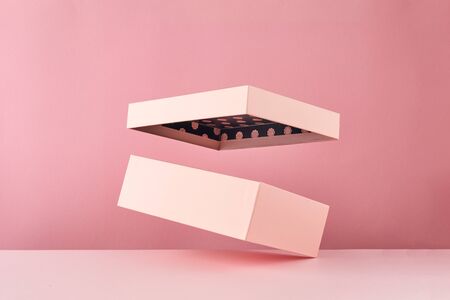 Pink open gift box isolated on pink background. Empty gift container. Mock up with flying box.