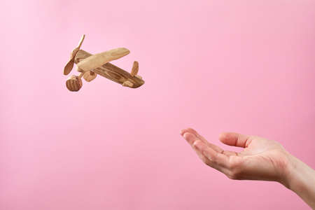 Concept soft landing or airline safety, security and insurance. Female hand and airplane on a pastel pink backgroundの写真素材
