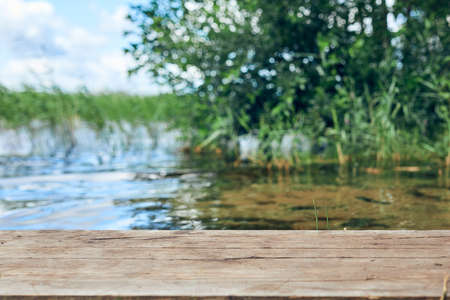 Empty wooden table with landscape background. Lake with mist and cloud. Focus on wooden desk table.の写真素材