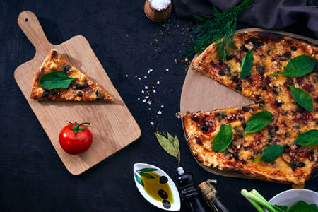 Italian pizza and pizza cooking ingredients on dark background. Tomatoes, olives oil, herbs and spices.の写真素材