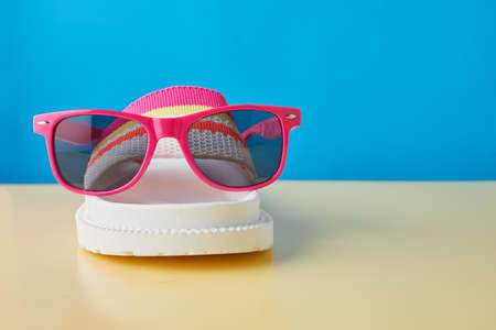 Summer travel concept. Flip flops or slippers and sunglasses on a pastel background. Beach...