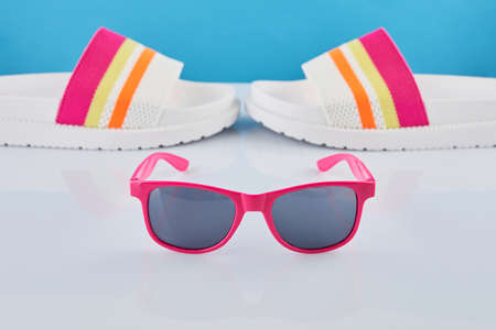 Summer travel concept. Flip flops or slippers and sunglasses on a pastel background. Beach accessories.の写真素材