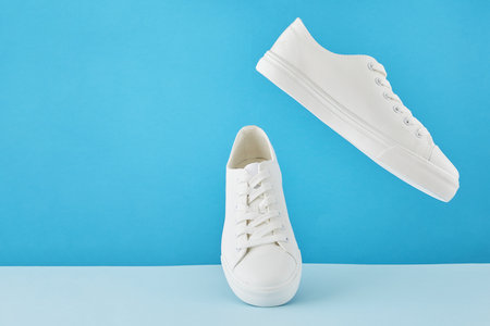 Pair of fashion stylish white sneakers, Running sports shoes on a pastel blue background.の写真素材