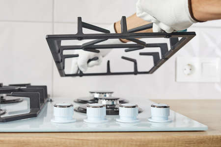 Male hand do installation burner on gas hob in kithen, close up. Repairs or fix of gas control...