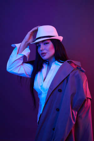 Portrait of young woman in coat and hat in the studio with color filters. Fashion neon concept.の写真素材