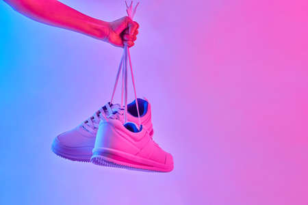 Fashion white sneakers in neon light. Sport shoes for training in the gym. Creative minimalism.の写真素材
