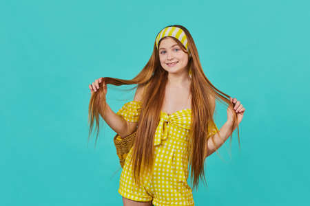 Portrait of funny emotional young girl on blue background. Pretty surprised lady in yellow dress...