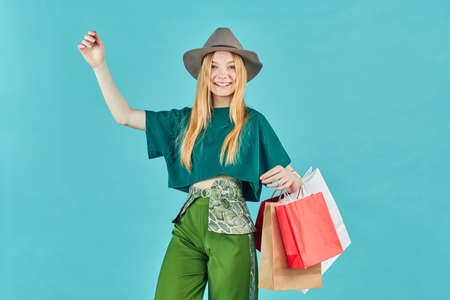 Happy young woman holding shopping bags staying. Pretty girl walk shopping center carry many packs...