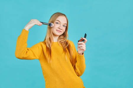 Happy girl with hairband hold brushes for makeup. Blush or eye shadows. Teen fashion. Cosmetics for young skin. Hide skin problems.の写真素材