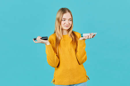 Girl holds tube with cosmetic cream. Teen girl doesn't like moisturizer, oil, wellness, exfoliator,...