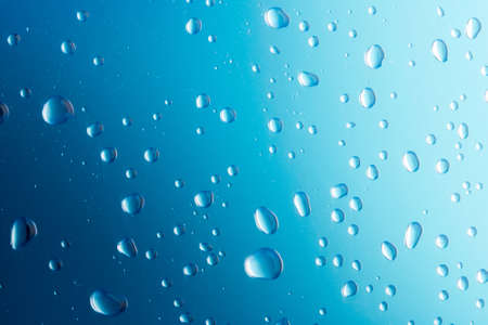 Water drops on blue background. Drops of water on surface. Macro photo. Splash pattern. Close-up.
