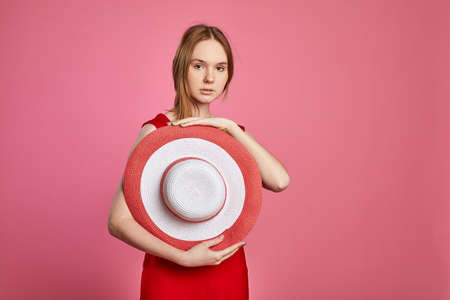 Fashion portrait of woman wearing hat. Young girl dressed in summer hat posing on pink background.の写真素材