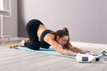 Woman In Fitness Wear Doing Exercise At Home. Time for yoga. healthy girl doing exercises while...