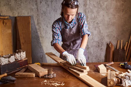 Business woman working as carpenter in a small carpentry workshop. Female carpenter working in carpentry shop with pencil drawing sign on plank.の写真素材