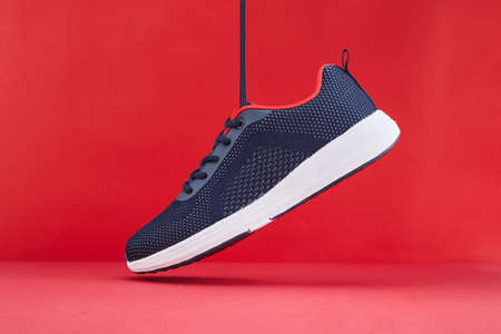 Colorful sport footwear or shoes on red color background. Running fashion blue sneakers for fitness...