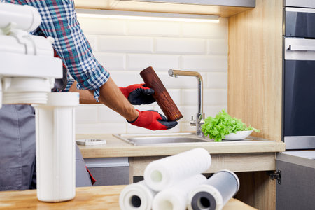 Plumber installs or change water filter. Replacement aqua filter. Repairman installing water filter cartridges in a kitchen. Installation of reverse osmosis water purification system.の写真素材