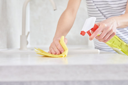 Close-up of female hands wiping the kitchen counter with a soft cloth. The concept of a housewife doing housework. Eco friendly house.の写真素材