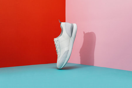 Stylish trendy shoes hanging on color paper background. Men's fashion sport footwear. Air sneakers. Creative minimal design. Flying leather sneakers isolated on a pastel background.の写真素材