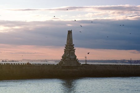 Old lighthouse with birds on a cloudy dayの写真素材