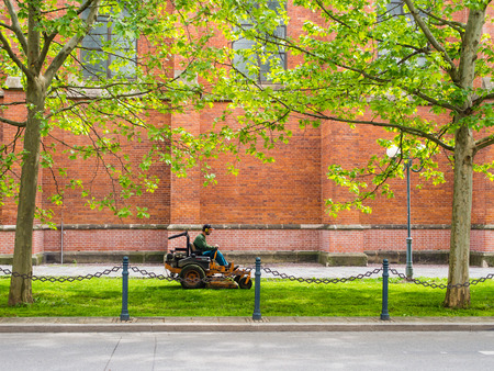 Public servise: Man on a mower cutting grass in the cityの写真素材